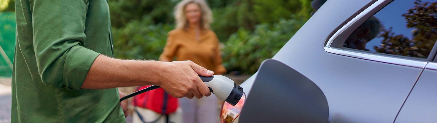 man charging electric vehicle