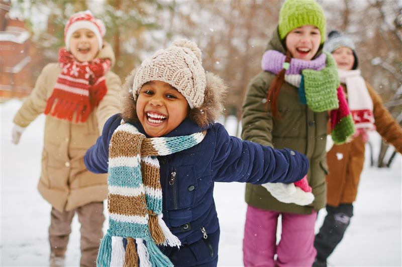 Children playing in the snow with hats and gloves on